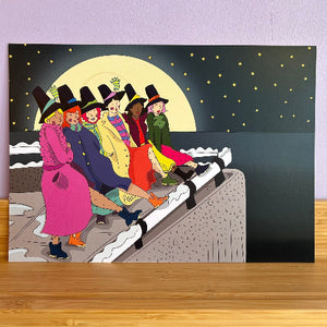 A square art print, depicting five women in colorful winter clothing sitting on a snowy ledge under a large full moon and starry sky.