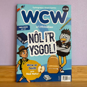 A Welsh school magazine titled 'WCW a'i ffrindiau' with school-themed illustrations, including a bird, a boy, a backpack, and a pencil.