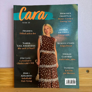 A copy of the Cara magazine, May 2026 issue, featuring a blonde model in a brown and white patterned dress on the cover, displayed on a wooden surface against a light wall.
