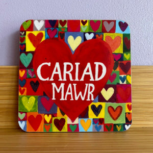 Colorful heart-shaped coaster with 'Cariad Mawr' text on a wooden surface.