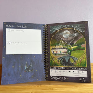 Open notebook with artistic cover and interior pages on a wooden surface.