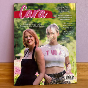 Magazine cover with two women on a wooden surface