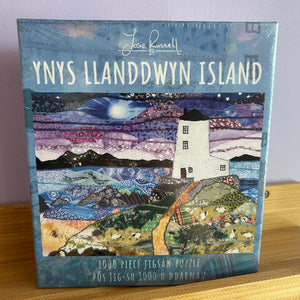 Jigsaw puzzle box featuring a lighthouse on Ynys Llandwyn Island with 'Josie Russell' branding.