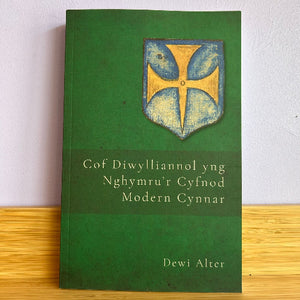 Green book with a gold and blue emblem on a white background