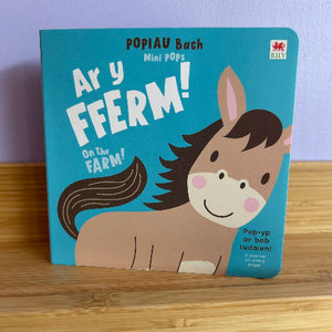 Children's book titled 'On the Farm' with a horse illustration on a wooden surface.
