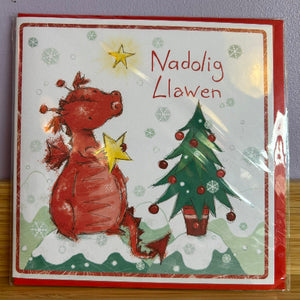 Christmas card with a dragon and tree design, featuring the Welsh greeting 'Nadolig Llawen'.