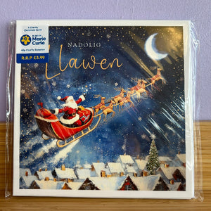Christmas card with Santa Claus in a sleigh, surrounded by reindeer, over a snowy village scene.
