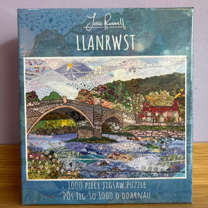 Jigsaw puzzle box featuring a scenic landscape with a bridge and buildings, titled 'Llanrwst' by Josie Russell.