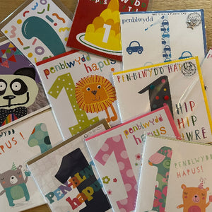 Collection of colorful greeting cards with various designs and text on a wooden surface.