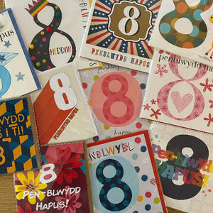 Collection of cards with various designs featuring the number '8' and Welsh text, including 'PENBLYWDD HAPUS'.
