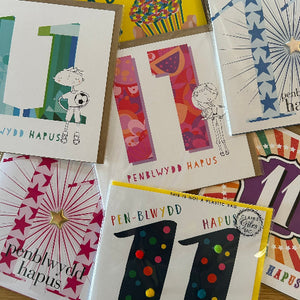 Collection of greeting cards with various designs and text on a wooden surface.