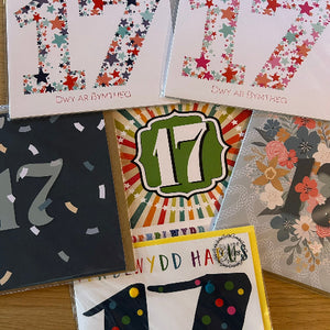 Collection of greeting cards with various designs and the number 17 on a wooden surface.