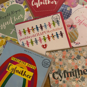Collection of greeting cards with 'Cyfnither' text and colorful designs.