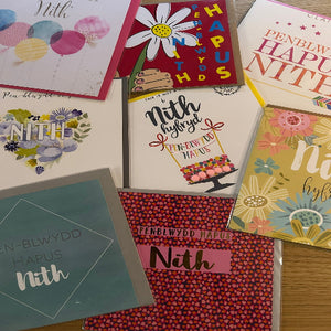 Collection of greeting cards with various designs and text on a wooden surface.