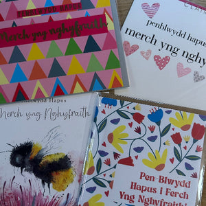 Four greeting cards with different designs and text on a wooden surface.