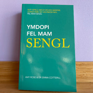 Green book titled 'YMDOPI FEL MAM SENG' with yellow text on a wooden surface and purple wall background