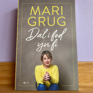 Poster with a woman in a yellow sweater and text on a wooden surface and purple wall background