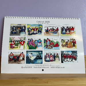 Calendar 2026 with illustrations of people in traditional clothing on a wooden surface.