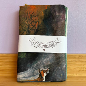 Tea towel with fox design and 'Llain Sychu' label on a wooden surface