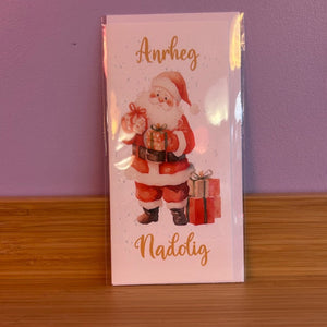Card with Santa Claus holding gifts against a purple wall.