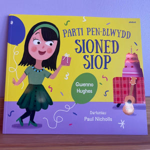 Children's book with a colorful cover featuring a girl, cake, and balloon on a purple and yellow background.