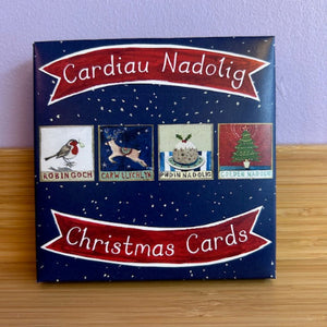 Box of Christmas cards with illustrations and text on a wooden surface.