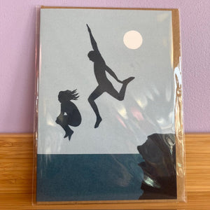 Silhouette of a person jumping over another on a card with a moon in the background