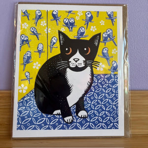 Greeting card with a black and white cat illustration on a yellow and blue patterned background.