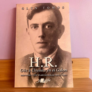 Book cover with a portrait of a man and text on a wooden surface with a pink background