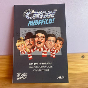 Book cover of 'Huw Mor Cymry Midffild!' with a group of people on a black background
