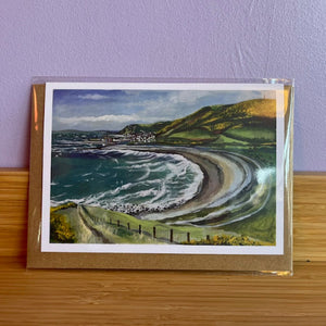 Greeting card with a scenic illustration of a beach and hills on a purple wall.